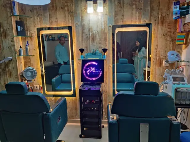 An empty salon interior with navy blue styling chairs, mirrored stations and pendant lighting.