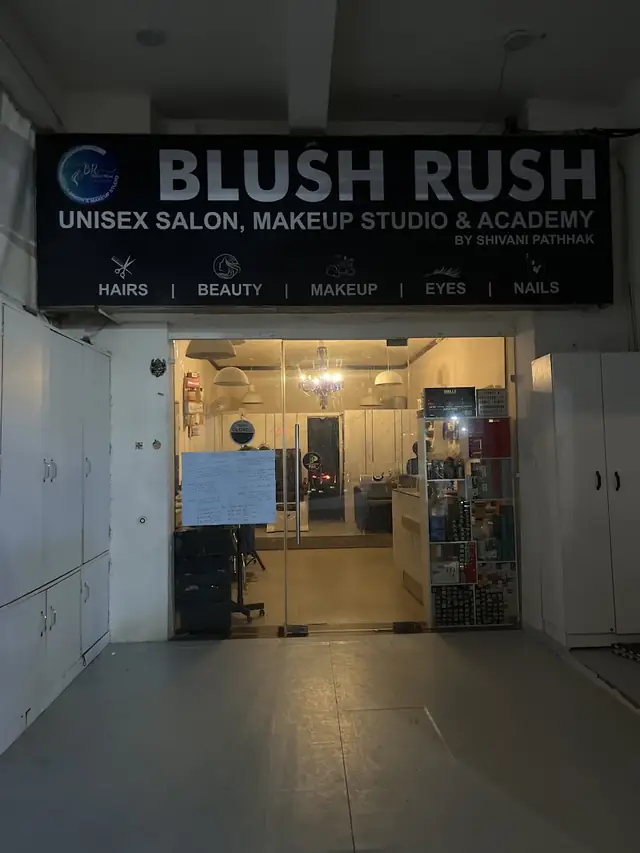 A row of salon mirror stations with navy chairs and a lit 'BR' logo sign on the wall.